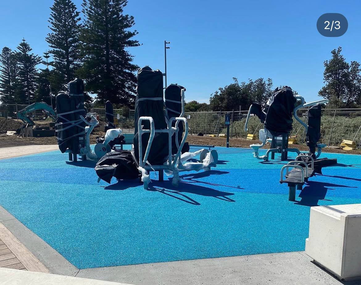 Blue wet pour rubber softfall installed under an outdoor gym fitness equipment station