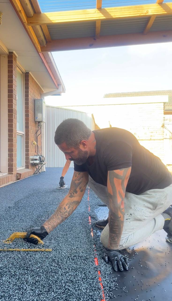 Mitchell, founder of Rubber Floor Solutions, hand-finishing a wetpour rubber surface on site